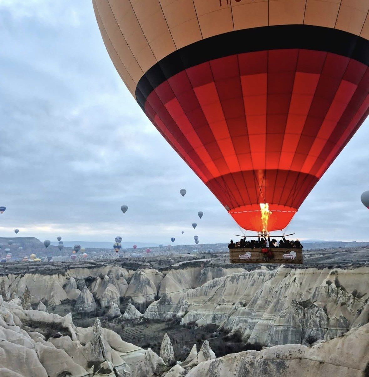 Passengers packed in a red balloon basket over Cappadocia's white rock valley