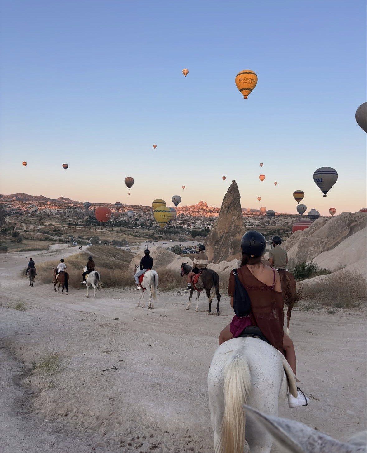 Group riding horses on a dusty Cappadocia track at blue dusk